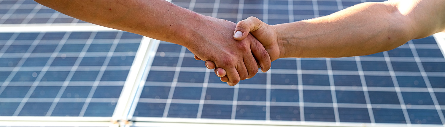 Händeschütteln vor einer Solaranlage nach Abschluss des Vertrags über erneuerbare Energien